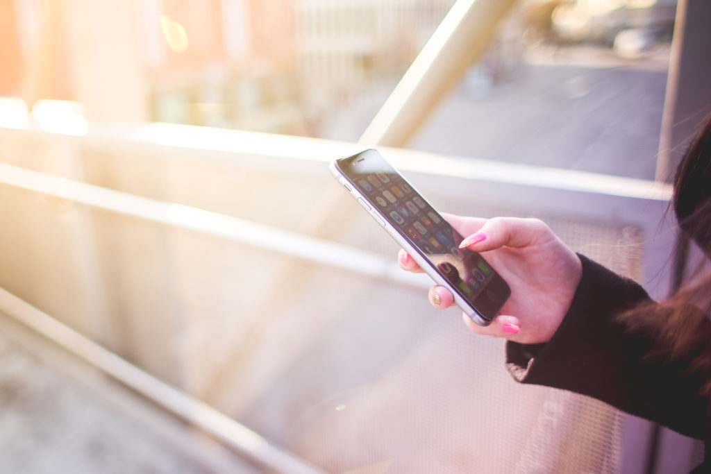 young-woman-holding-iphone-in-her-right-hand-picjumbo-com