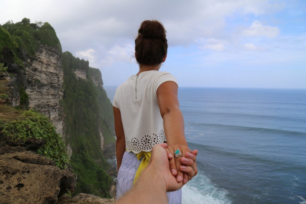 woman-by-cliff-holding-mans-hands