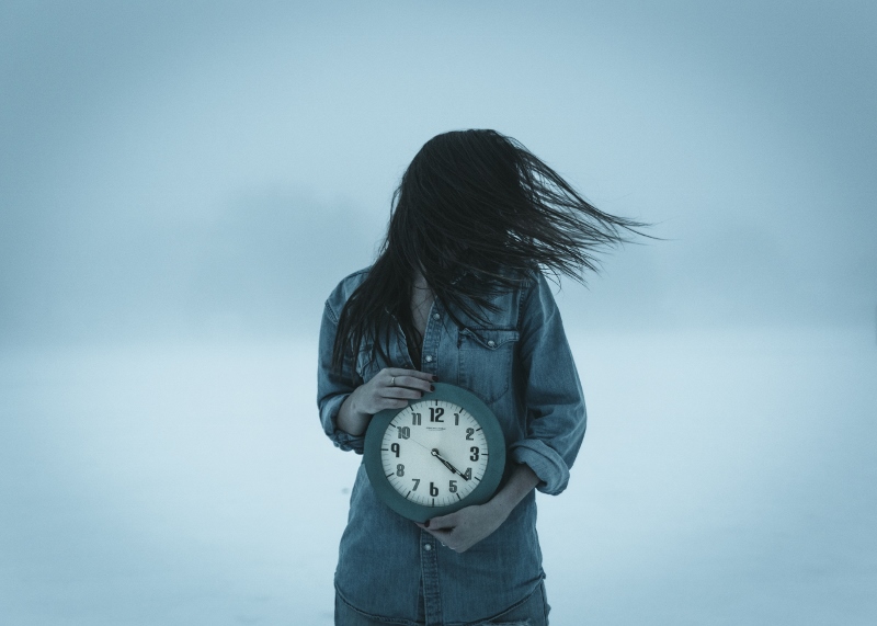 woman holding clock in strong wind